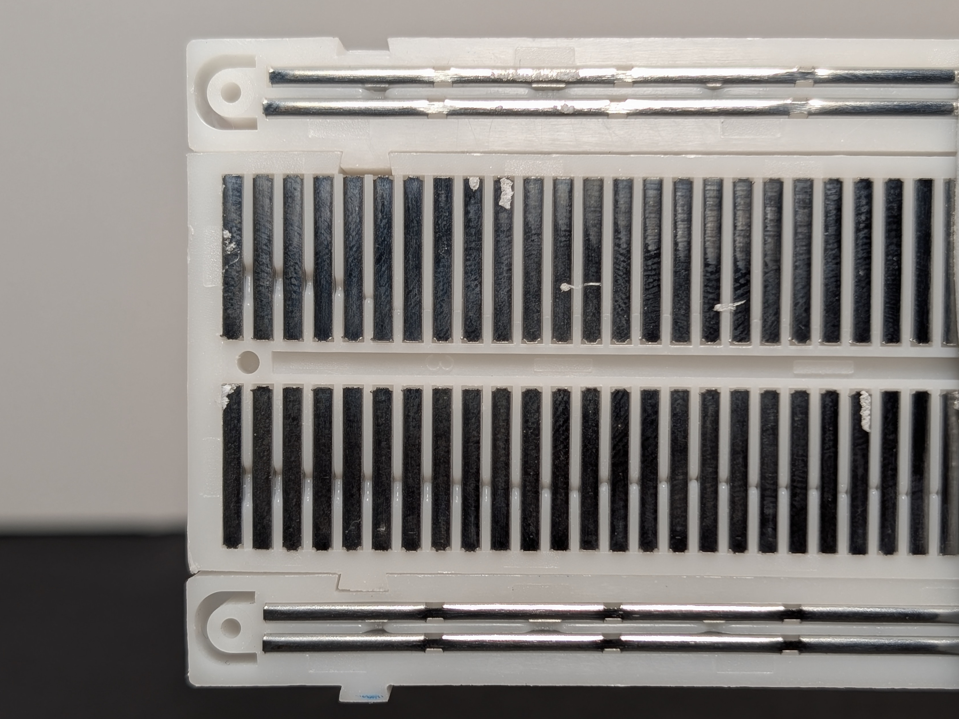 Photo of the same breadboard with the back removed so the metal strips inside are visible