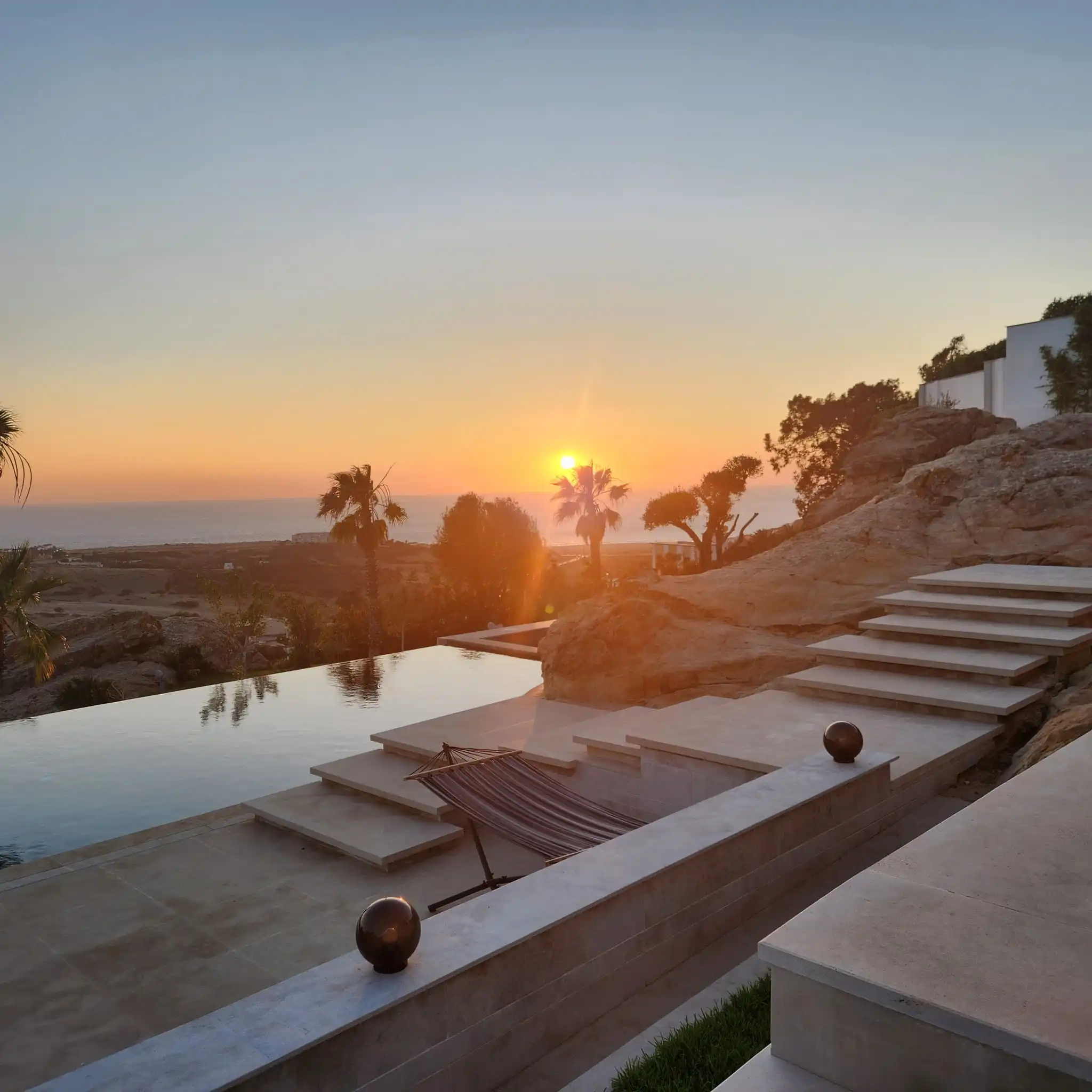 a view of the sunset from the pool at a luxury villa
