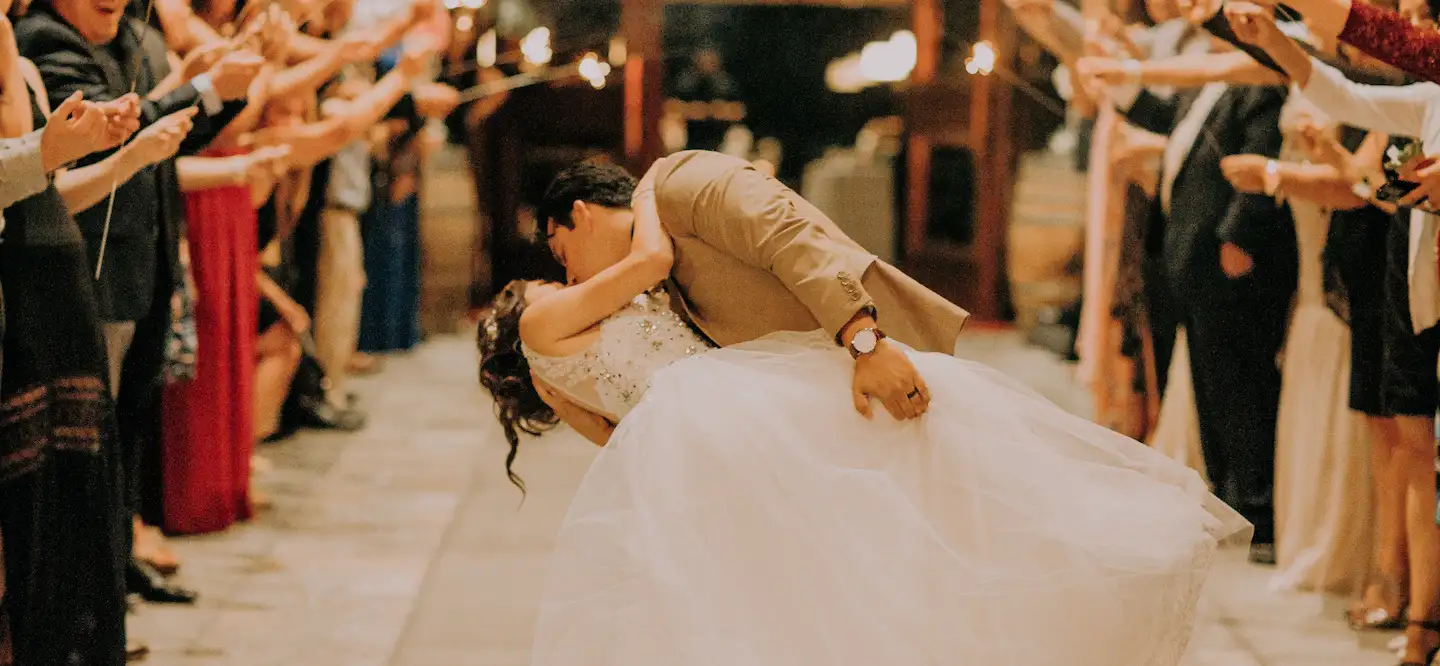 Photo de jeunes mariées qui s'embrassent sous les applaudissements de leur convives