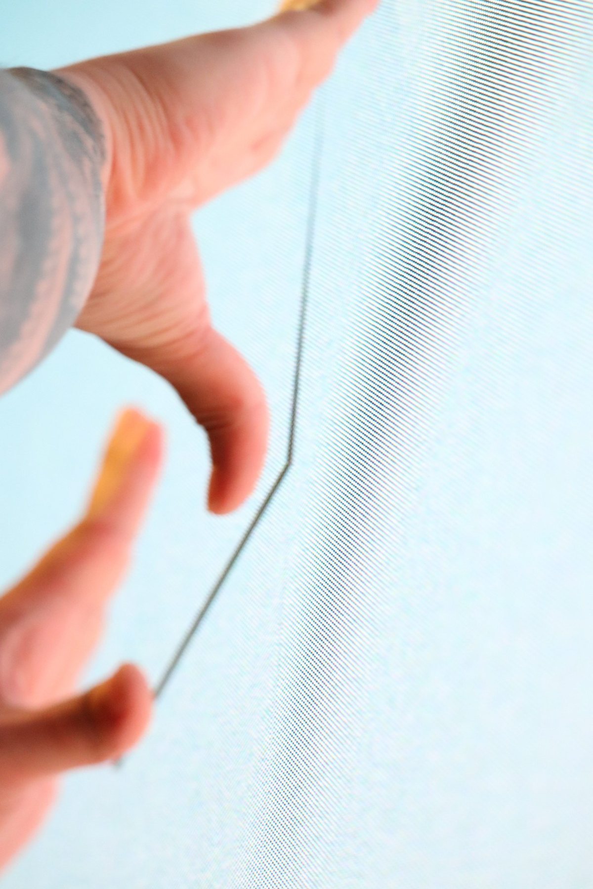 A hand guiding a cable behind a display