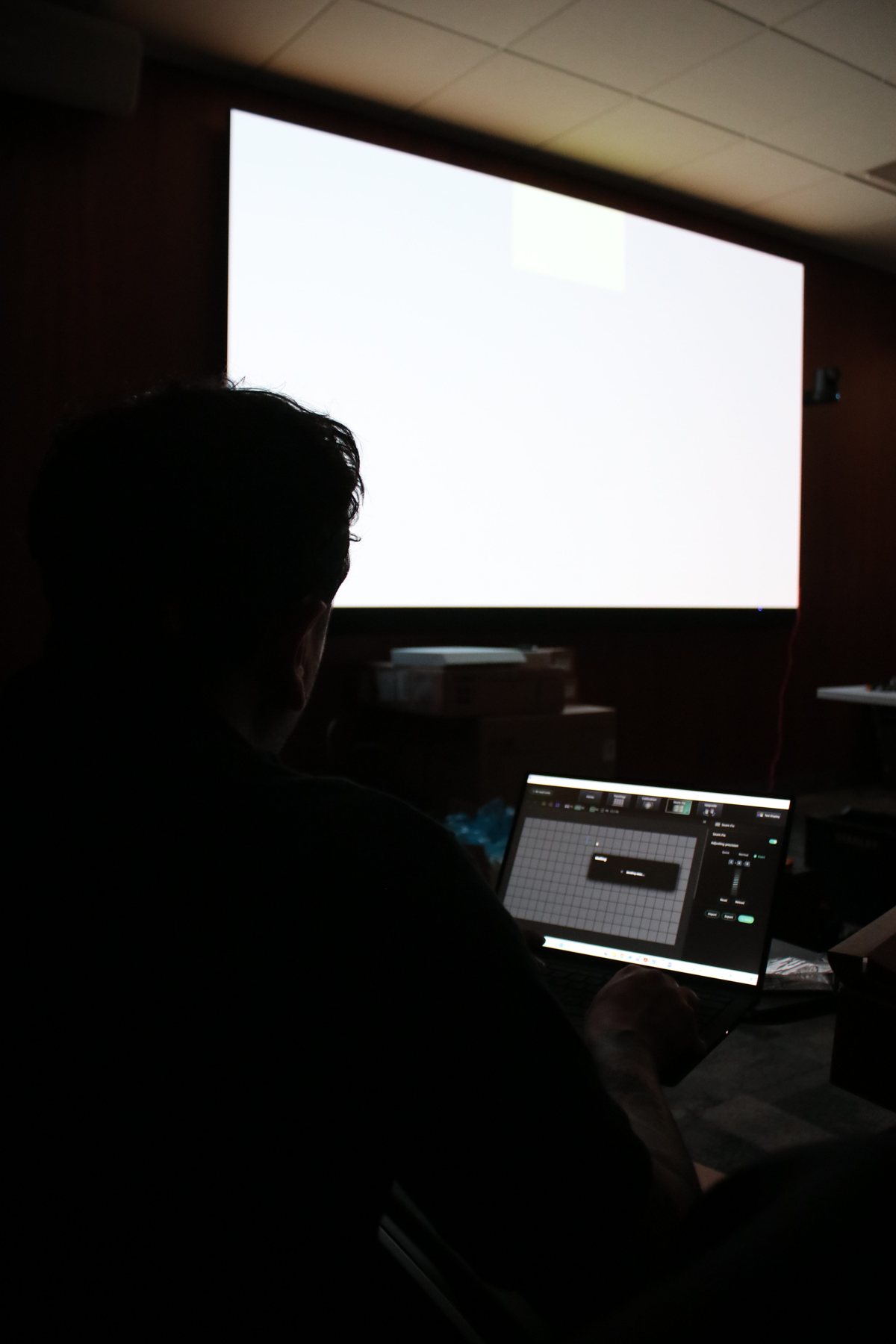 A technician at a laptop running diagnostics in a dark room