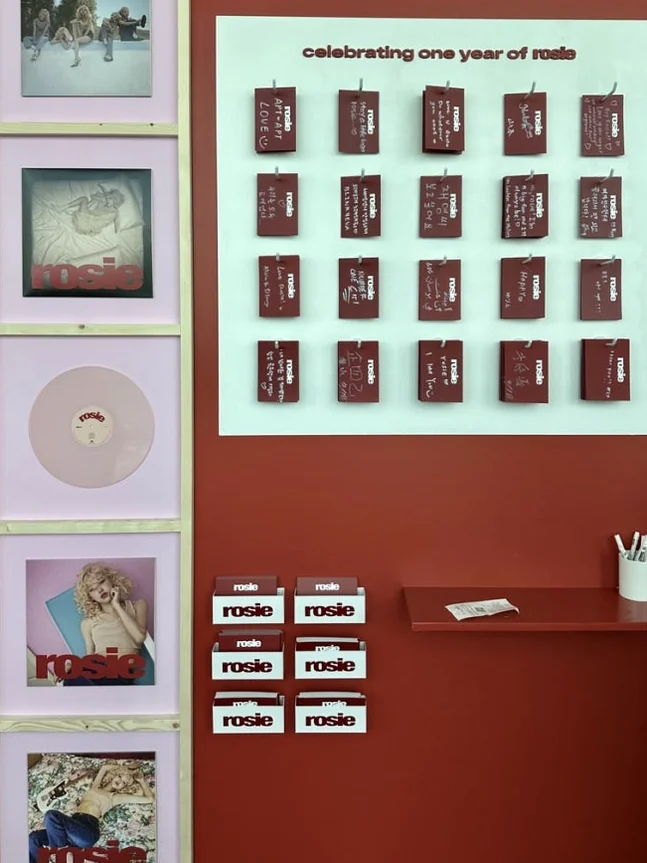 A curated display table showcasing limited edition pop-up merchandise, including artfully designed postcards and an array of unique collectibles - ROSÉ ENCORE POP-UP in BUSAN: A Deep Dive into 'one year of rosie' at BUSAN X the SKY