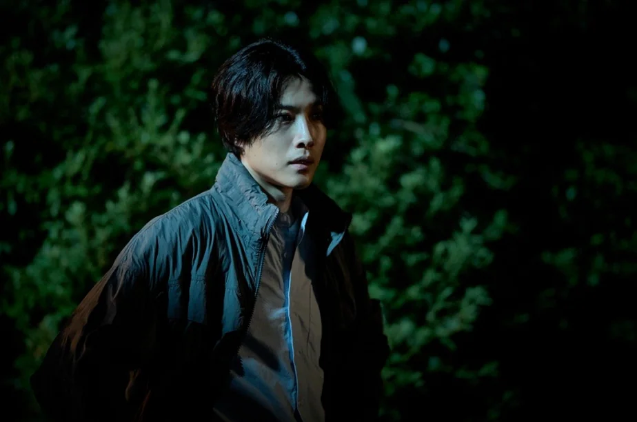 暗い葉を背景に、決然とした表情を見せる長髪の男性の横顔 - 韓国を震撼させる映画『サルモクチ』の世界。忠清南道・礼山への聖地巡礼ガイド