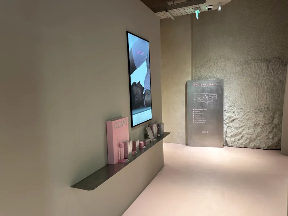 alt: ミニマルな棚に展示されたピンクの製品パッケージとデジタルスクリーン - 江南の美の殿堂｜Cclime Beauty Museumで体験する究極の小顔デザイン