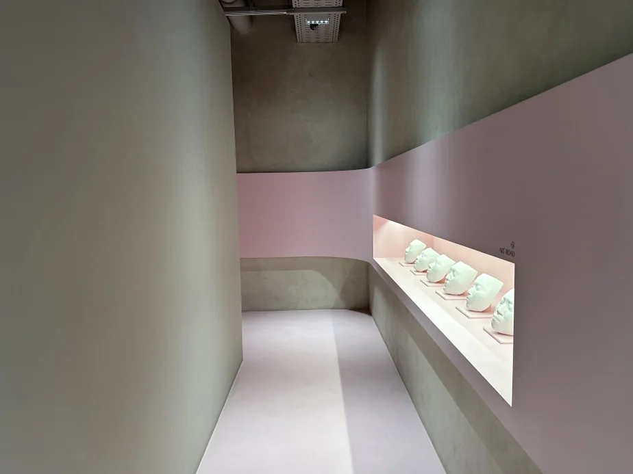 alt: 壁面に埋め込まれた石膏マスクのディスプレイが印象的な廊下 - 江南の美の殿堂｜Cclime Beauty Museumで体験する究極の小顔デザイン