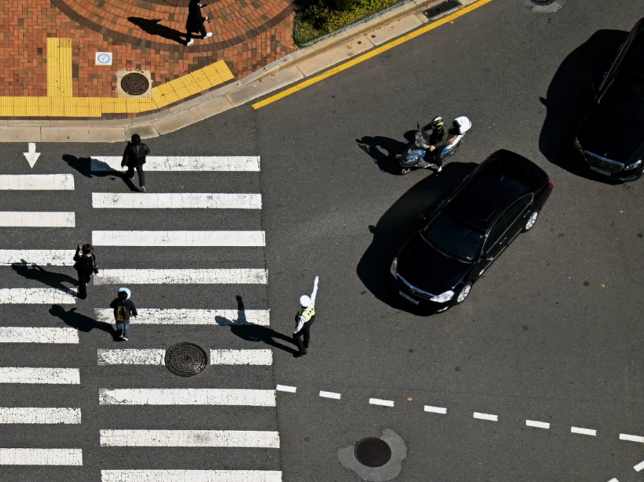 A textured medium shot of a roadside traffic sign standing against the backdrop of a busy city street - Navigating the Pause: The Essential 2026 Guide to Korea’s Right-Turn Regulations