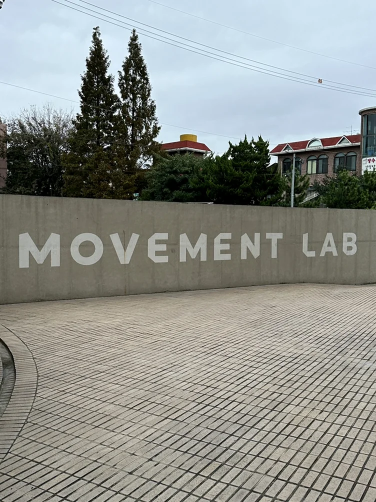 alt:広場を背景にした、白い'MOVEMENT LAB'のロゴがあるコンクリートの外壁 - ソウル近郊の美学、ムーブメントラボ義王で体験する究極のインテリア・キュレーション