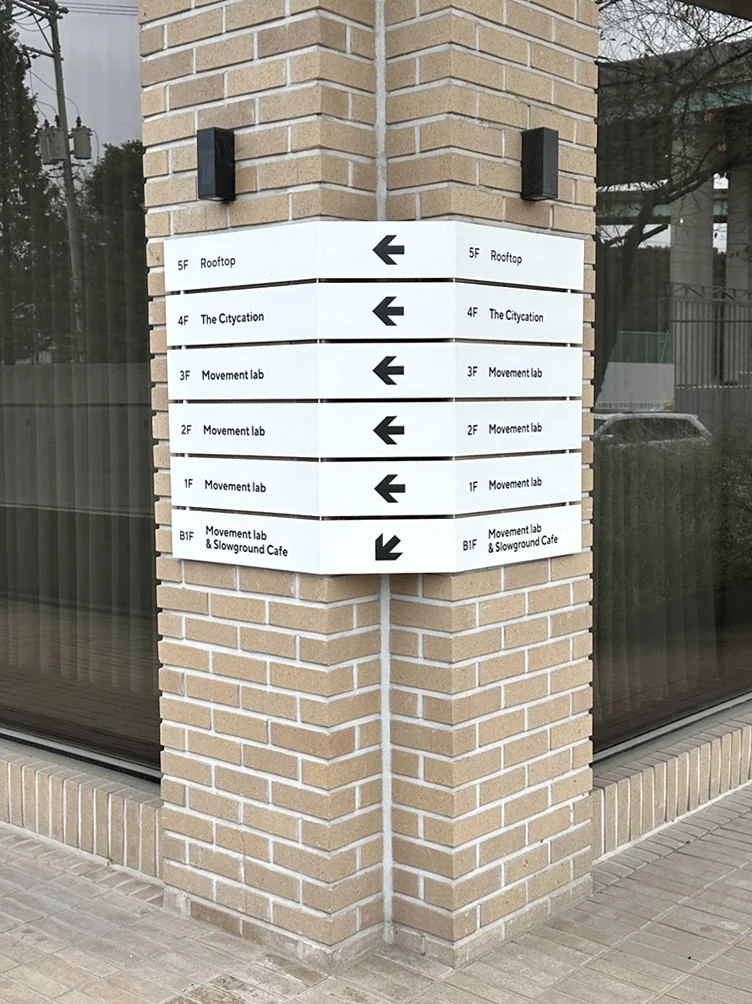 alt:各フロアやゾーンを案内する、レンガの柱に設置された情報サイン - ソウル近郊の美学、ムーブメントラボ義王で体験する究極のインテリア・キュレーション