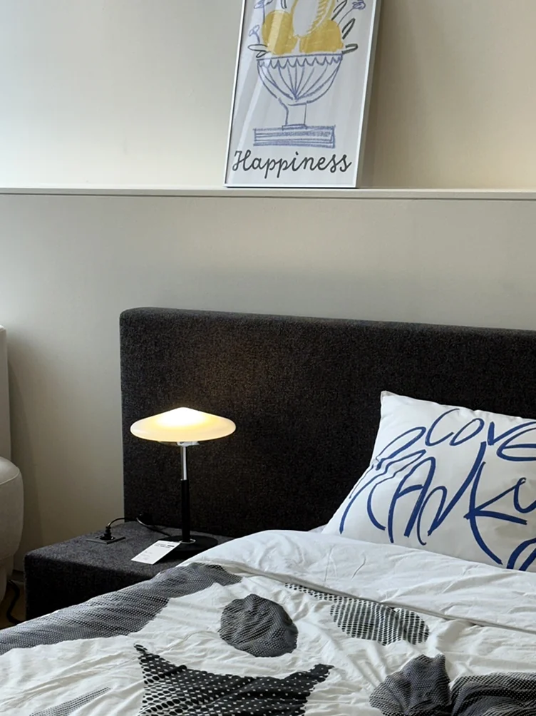 alt: 'Happiness'のポスターと柔らかな間接照明が置かれたヘッドボードシェルフのクローズアップ - ソウル近郊の美学、ムーブメントラボ義王で体験する究極のインテリア・キュレーション