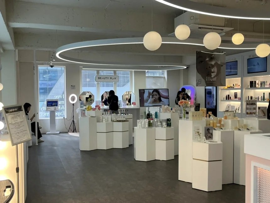 The wide-angle perspective of the minimalist showroom featuring contemporary circular lighting and neatly arranged product displays. - Unlocking the K-Beauty Ethos: A Discerning Guide to Beauty Play Hongdae