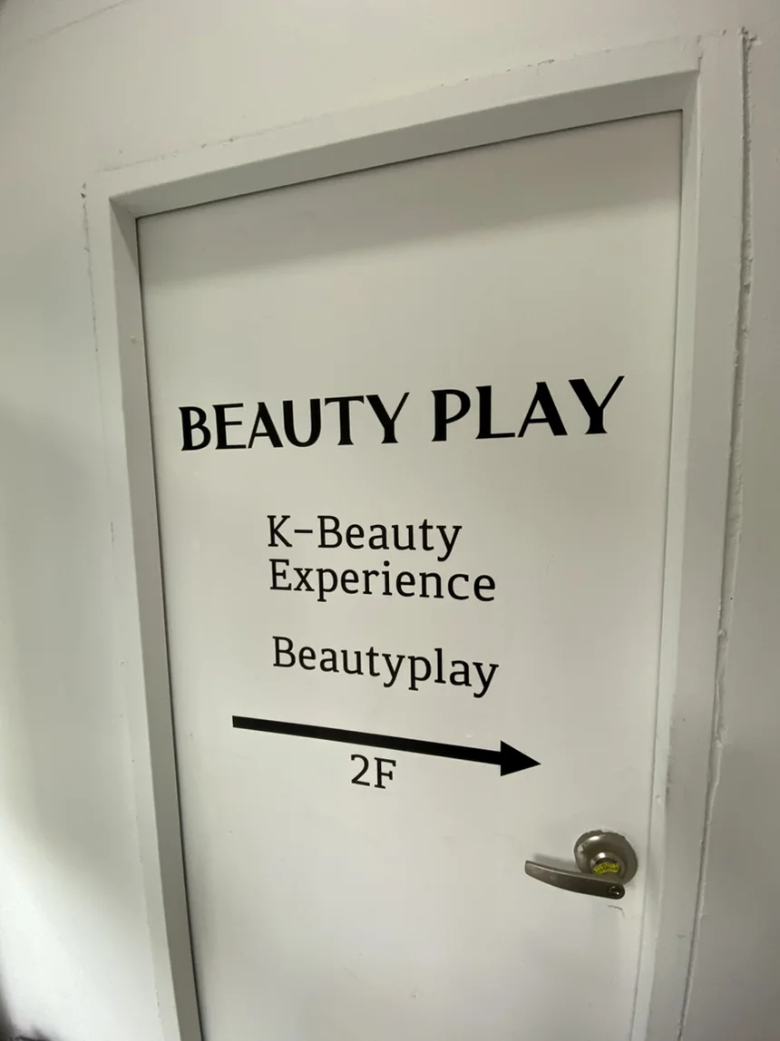 A minimalist white door displaying clean black typography for directional guidance between the brand and experience zones. - Unlocking the K-Beauty Ethos: A Discerning Guide to Beauty Play Hongdae