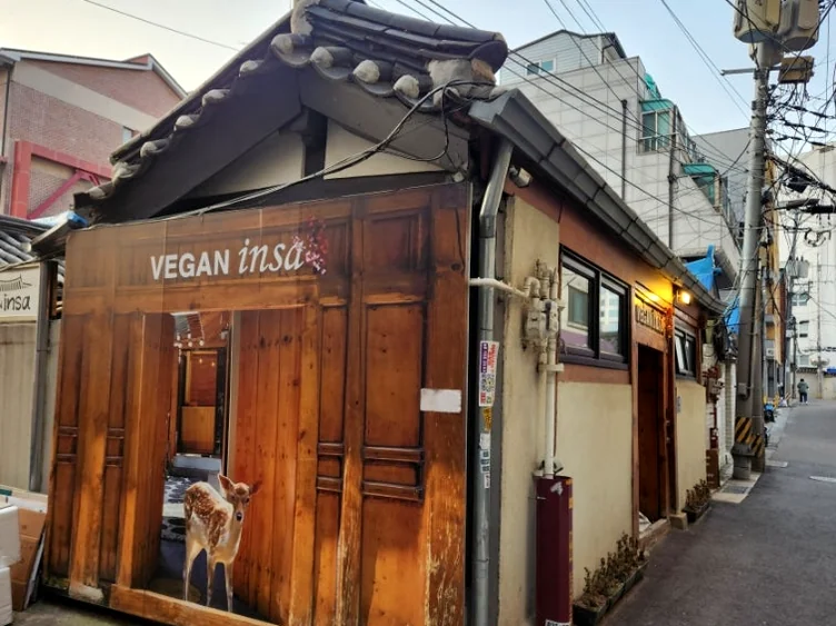 A detailed look at the artistic mural and the textured wooden exterior of the restaurant - A Sanctuary of Plant-Based Heritage: Exploring the 100-Year-Old Hanok of Vegan Insa