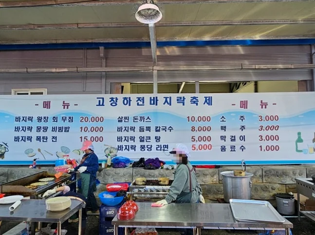 alt: フェスティバルのダイニングエリアで撮影された大きな物理的なメニューボード。会場の環境に合う実物を通じて重要な情報を提供しています。 - 『K-Life Hack』厳選！高敞ハジョンアサリ五感体験フェスティバルで贅沢な韓国の自然を満喫する旅