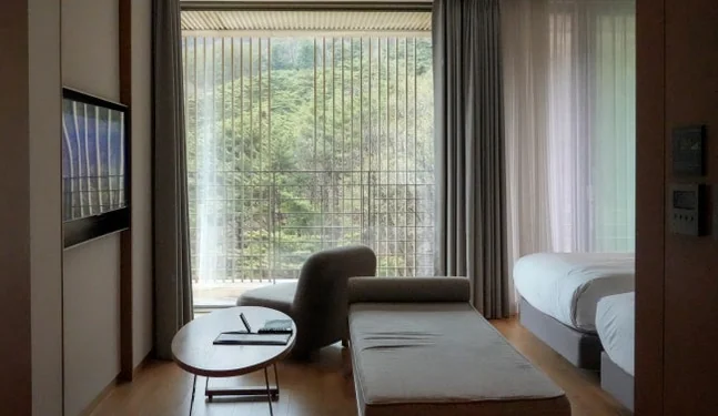 深い森を望む大きな窓が特徴的なプレミアムホテルのスイートルーム。堤川でのラグジュアリーな滞在を表現。 - 癒やしと歴史が交差する、忠清北道・堤川「義林池」の極上トラベルガイド