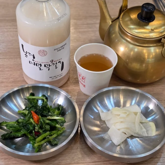 真鍮の器に注がれた伝統的なメミルマッコリと、地元の素朴なダイニング風景。 - 癒やしと歴史が交差する、忠清北道・堤川「義林池」の極上トラベルガイド