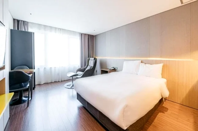 An elegant single-bed room featuring warm lighting and a cozy entertainment area perfect for the solo traveler - A Curated Stay in Seogwipo: The Unrivaled Value of The First 70 Hotel