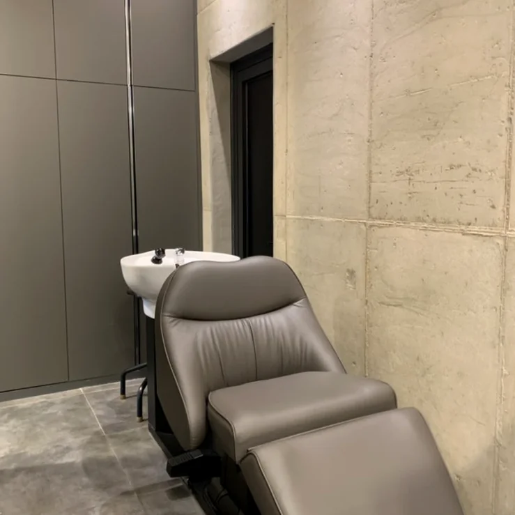 Luxurious leather hair-wash lounge station set against a modern concrete textured wall showing premium equipment - Architectural Volume: The Discerning Expats Guide to The Objet Cheongdam