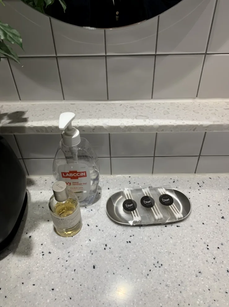 Close-up of luxury amenities and perfumes provided for clients in a clean marble-finished powder room area - Architectural Volume: The Discerning Expats Guide to The Objet Cheongdam