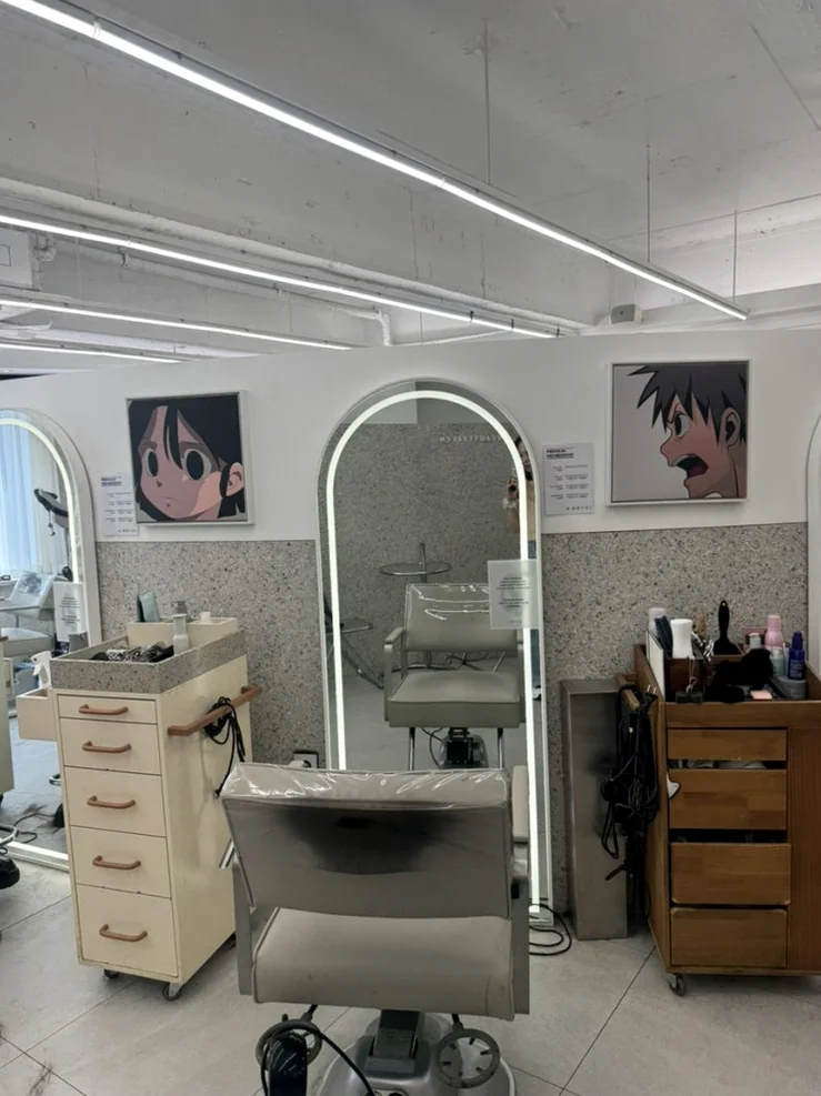 An artistic hair station with an arched illuminated mirror and unique character illustrations on the wall - Beyond the Neon: The Precision of K-Beauty Mastery at Argyol Hongdae
