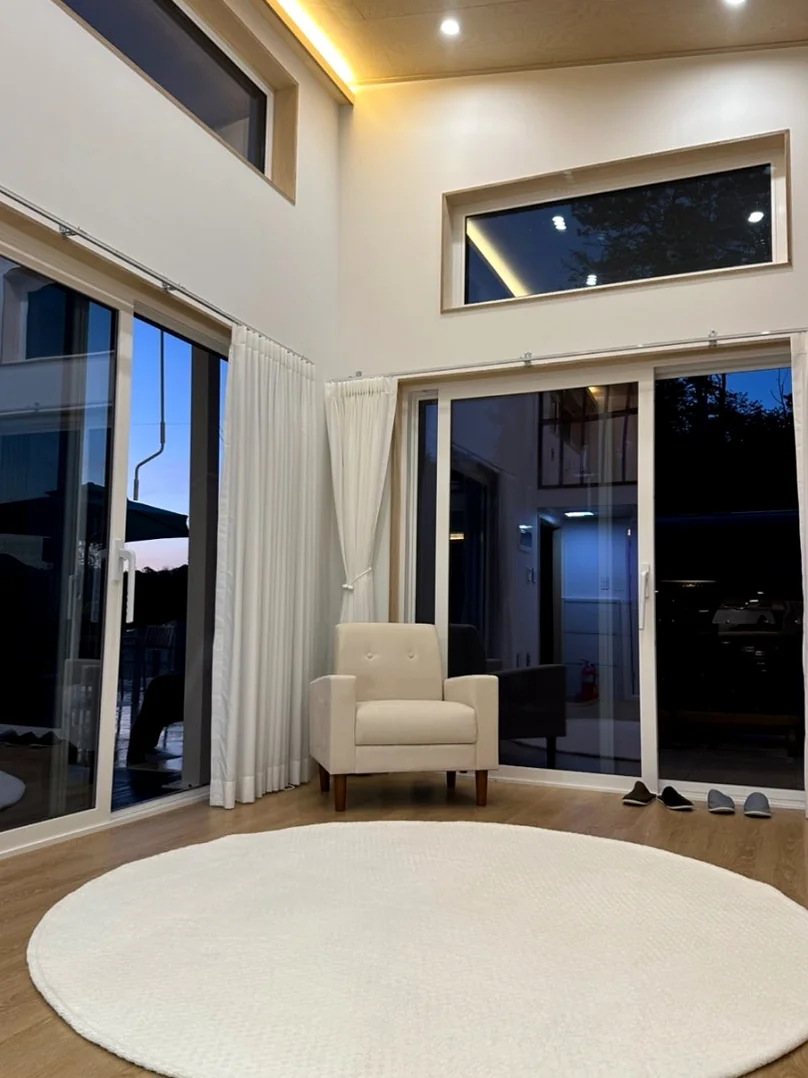 The minimalist interior of the villa's living area with high ceilings, large glass doors, and a soft circular rug. - The Vertical Elegance of 죽녹원: A 2026 Masterclass in Bamboo Minimalist Living