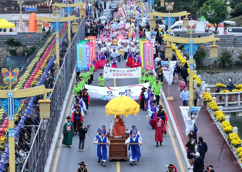 A grand parade featuring participants in traditional Korean costumes crossing a bridge during the Miryang Arirang Festival, with the river and city in the background. - The 68th Miryang Arirang Festival: A Timeless Korean Cultural Spectacle