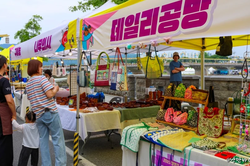 A vibrant market stall under a tent with a '데일리공방 (Daily Workshop)' banner, displaying a diverse range of handmade goods and ceramics. - The 68th Miryang Arirang Festival: A Timeless Korean Cultural Spectacle