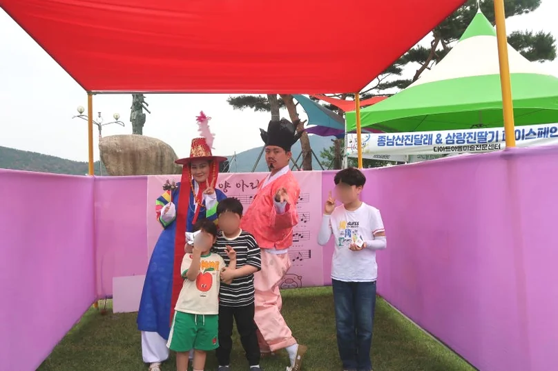 Performers in colorful traditional Korean costumes posing with children in a festive tent at the festival ground. - The 68th Miryang Arirang Festival: A Timeless Korean Cultural Spectacle