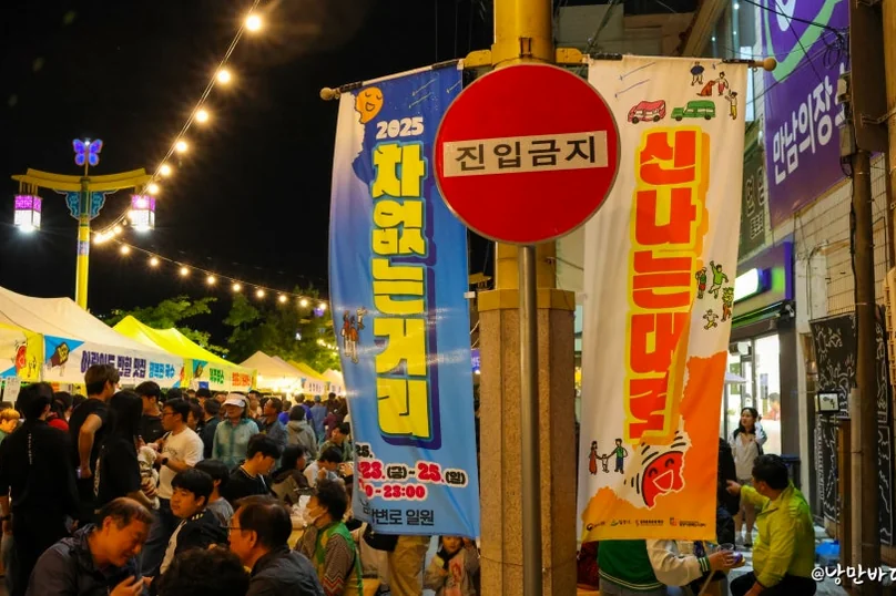 A lively night street scene during the festival, adorned with string lights and banners, featuring a red 'No Entry' sign and crowds of people. - The 68th Miryang Arirang Festival: A Timeless Korean Cultural Spectacle