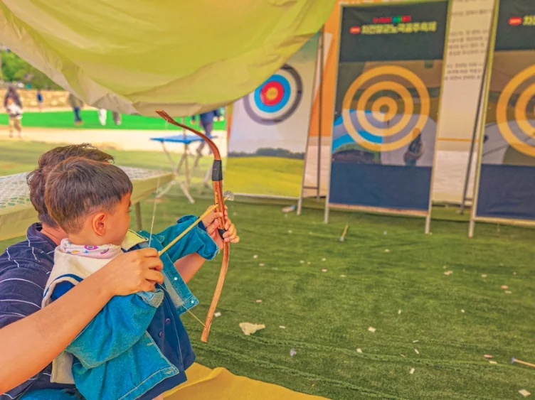 alt="インストラクターの指導のもと、真剣な表情で韓国の伝統的な弓術を体験する少年" - 2026年5月の韓国旅行、安東（アンドン）へ。伝統と遊びが融合する「車戦将軍・魯国公主祭り」完全ガイド