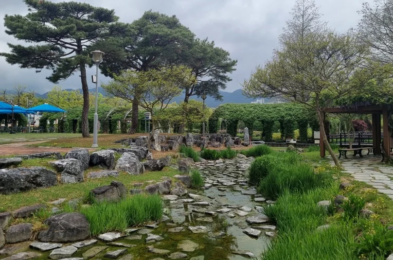 A rock-lined stream flowing through the park, adding the soothing sound of water to the sensory experience of the garden. - The Floral Monarchy: Rediscovering Nostalgia at Gokseong Seomjingang Train Village