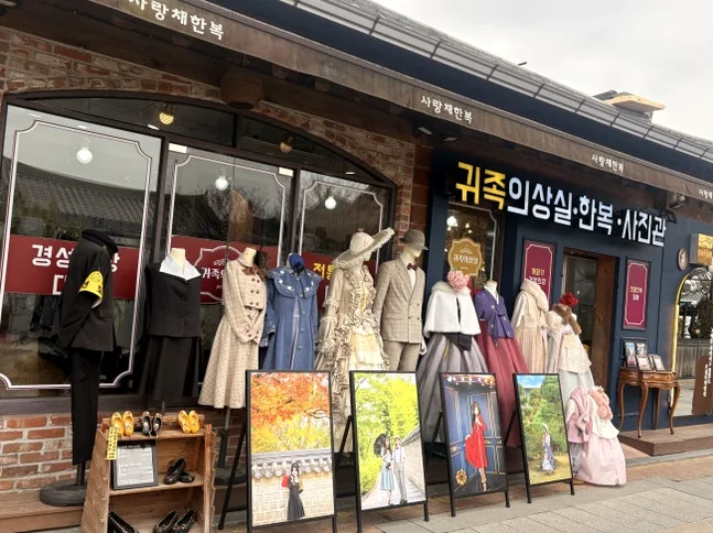 全州韓屋村にあるブティックの店先の広角写真。様々な韓服と時代物のドレスがマネキンに展示され、レンタル可能です。 - 全州韓屋村で優雅な韓服体験：『貴族衣装室』で叶える特別な一日
