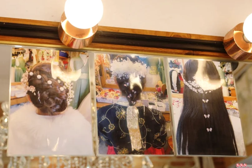 鏡に貼られたヘアスタイル参考写真のクローズアップ。真珠を使った様々な伝統的な髪型が紹介されています。 - 全州韓屋村で優雅な韓服体験：『貴族衣装室』で叶える特別な一日