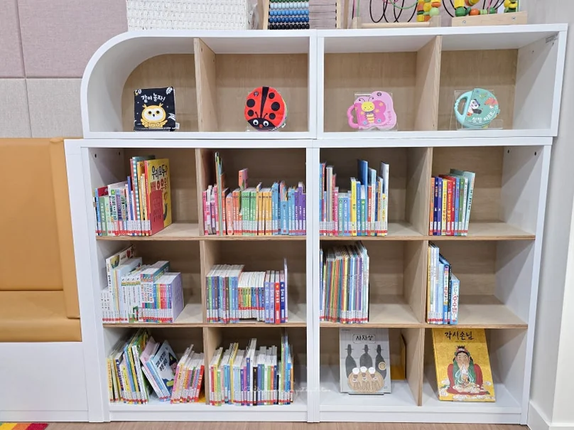Curated white bookshelves displaying a diverse collection of picture books, highlighting the library's thoughtful interior design tailored for young eyes. - Literary Luxury in Gangnam: The 2026 Great Children’s Day Festival at the National Library for Children and Young Adults
