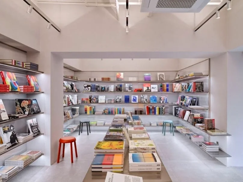 The spacious and thoughtfully designed main interior of MoMA Bookstore Seoul, where books are artfully displayed on central tables and perimeter shelves, illuminated by subtle lighting, creating an atmosphere of quiet discovery. - MoMA Bookstore Seoul: A Curated Sanctuary for Art and Design