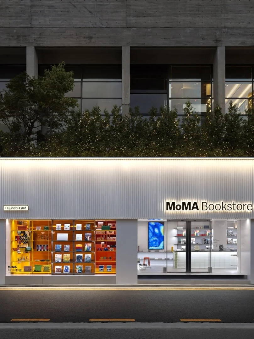 The MoMA Bookstore Seoul facade illuminated at dusk, its minimalist architecture aglow with warm interior lights, creating a sophisticated and welcoming ambiance against the twilight streetscape. - MoMA Bookstore Seoul: A Curated Sanctuary for Art and Design