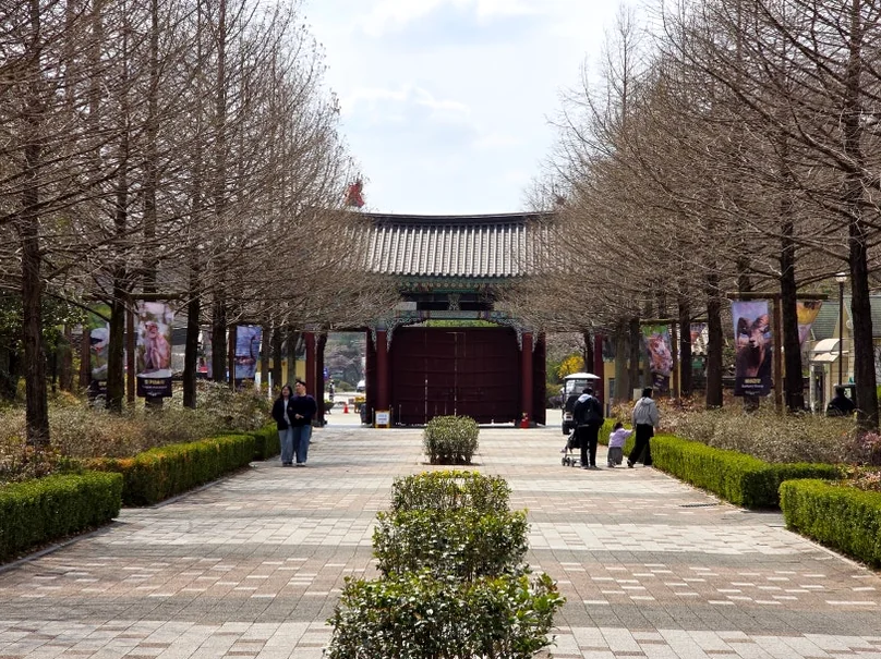 An elegant tree-lined promenade leading toward a traditional structure, showcasing the park's sophisticated landscape architecture. - Nostalgic Sanctuaries: Jeonju Zoo and the 2026 Eco-Aesthetic Evolution