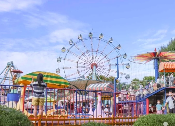 A high-quality wide shot of the vibrant amusement park area, featuring the majestic Ferris wheel against a soft blue sky. - Nostalgic Sanctuaries: Jeonju Zoo and the 2026 Eco-Aesthetic Evolution