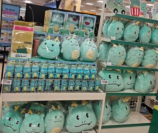 A shelf brimming with soft, cuddly Joayong plush toys, each featuring the character's unique, endearing expressions, inviting fans to take home a piece of this delightful world. - Joayong's Popcorn Journey: E-Mart Borajum's Premier Character Pop-Up