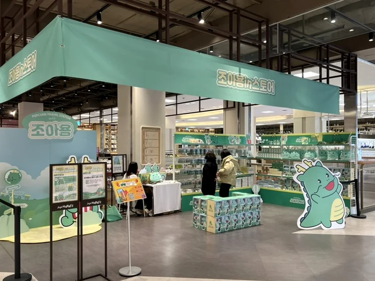 A close-up of the charming Joayong plush toys on display, with various character cutouts depicted in cars and hot air balloons providing a playful backdrop, enhancing the whimsical theme. - Joayong's Popcorn Journey: E-Mart Borajum's Premier Character Pop-Up