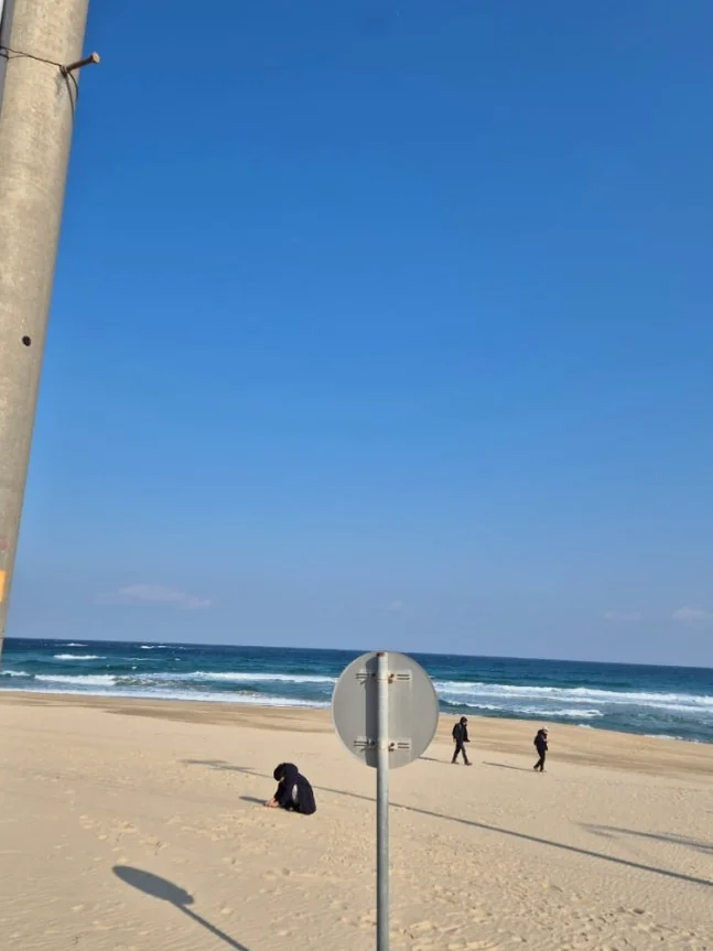 An individual with arms outstretched, experiencing a moment of profound serenity and freedom on the famed Jumunjin breakwater - Jumunjin's Dokkaebi Gelato: A Curated Coastal Escape Beyond the Screen