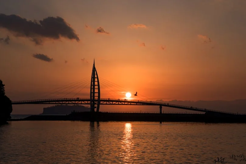 夕暮れ時に浮かび上がるセヨンギョの帆船シルエットの威容 - 西帰浦を象徴する光の彫刻、セヨンギョで迎える究極の週末：2026 金土金土セヨンショー