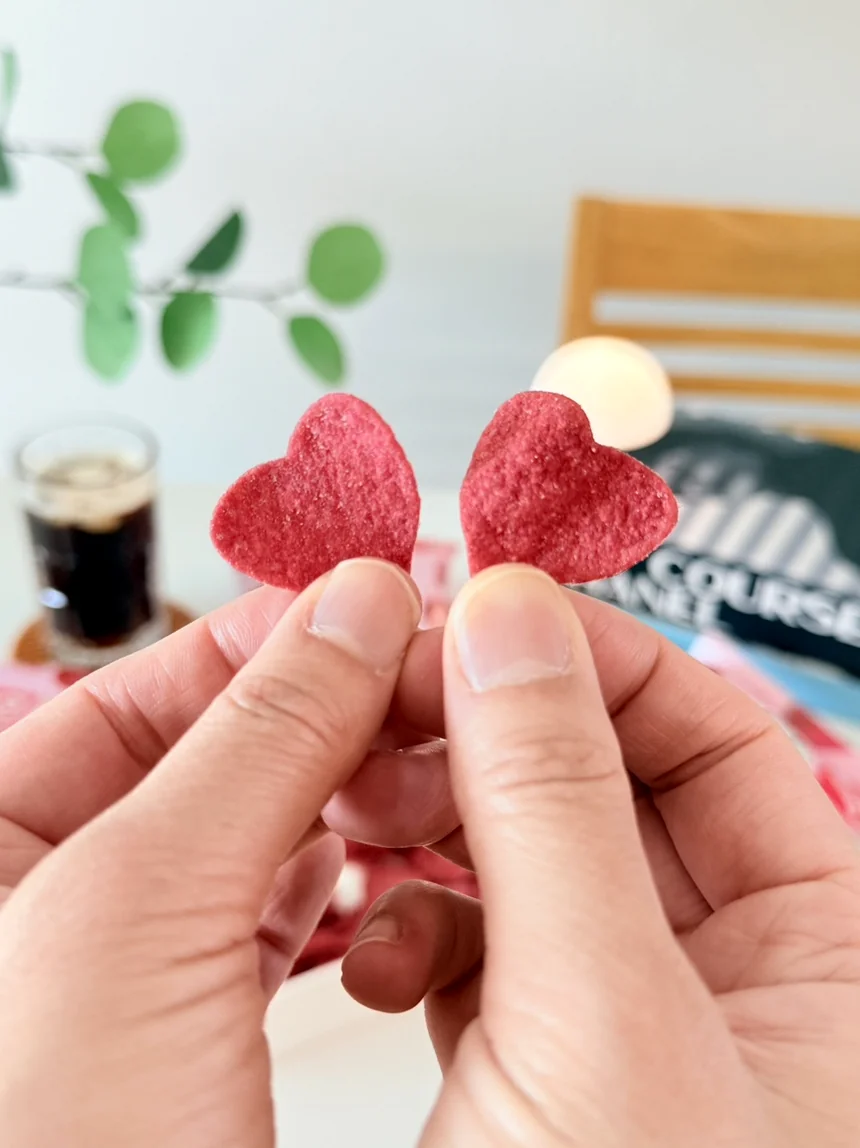 二つの手が優雅に掲げる一対의 하트형 프링글스 칩. 繊細なフォルムが光に照らされ、限定版スナックが持つ繋がりと魅力的なディテールを象徴している。 - 韓国限定・世界初の上陸。メガボックスとGSザ・フレッシュで出会う「プリングルズ・ハート・ミニ・ローズ」の誘惑