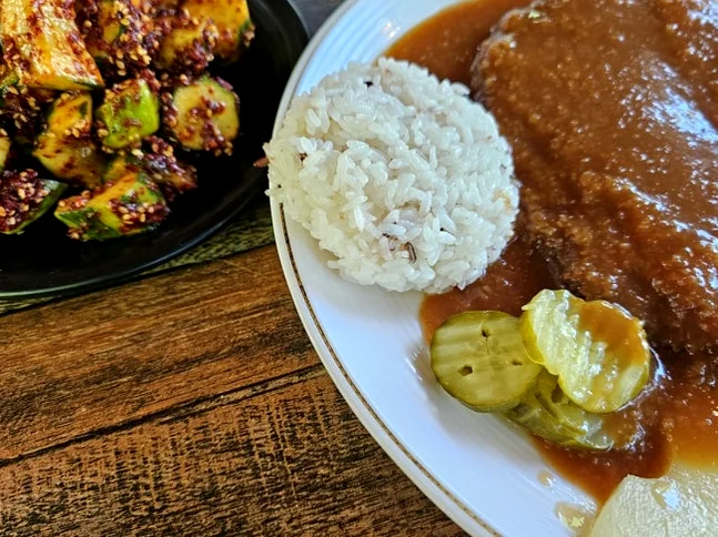 Signature pairing of sauce-laden TonKatsu and spicy seasoned cucumber salad. - The Culinary Hermitage of Suncheon: A Refined Guide to Songchi Maeul