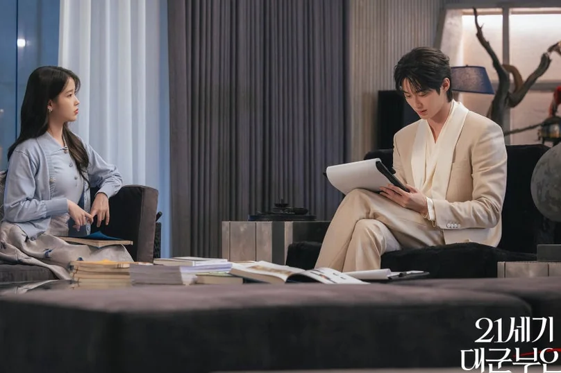 A visually steady scene of a conversation unfolding in a modern living space, marked by dramatic lighting and thoughtful character placement. - 21st Century Grand Prince's Lady: A Royal Romance Redefined (K-Drama Review)