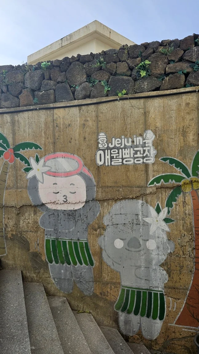 Outdoor wall mural featuring a cute character and the store logo representing Jeju vibes - Coastal Crust and Artisanal Calm: The Definitive Guide to Aewol Bread Factory Jeju
