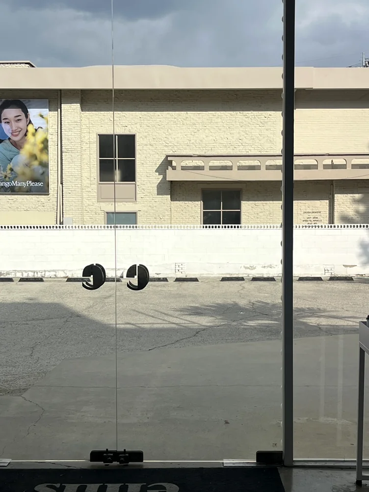 A minimalist entrance perspective showing the EMIS logo mat and the street view visible through the store's floor-to-ceiling glass - Defining the New Standard of K-Streetwear: Inside the EMIS Hannam Flagship Store