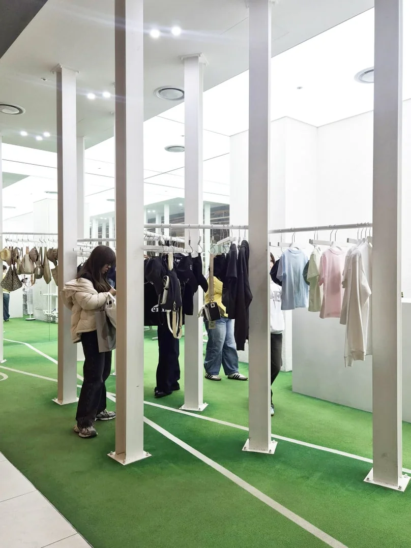 Wide-angle view of the interior space with vertical pillars and green flooring, creating a rhythmic architectural depth. - K-POPアイドルも夢中！ 韓国発「emis（イミス）」の魅力に迫る最旬ガイド ✨
