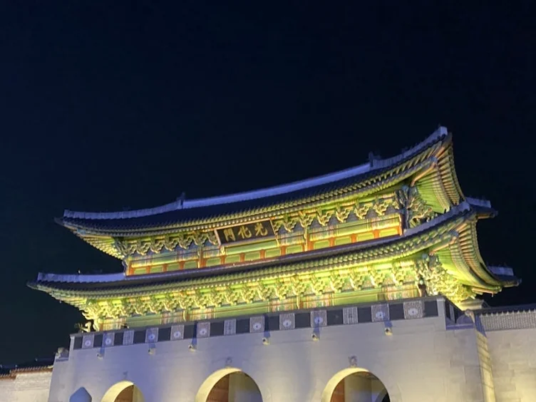 조명으로 극대화된 광화문의 위엄과 전통 목조 건축의 하부 디테일이 강조된 로우 앵글 컷 - 2026年春、ソウルの月明かりに包まれる「景福宮」夜間観覧完全ガイド