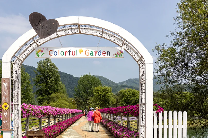 'Colorful Garden'이라는 문구가 있는 아치형 입구로, 꽃으로 장식된 통로를 통해 정원으로 들어서는 모습을 보여줍니다. 개방감 있는 구도로 방문객을 유혹하는 매력적인 안내 사진입니다. - Jaraseom Namdo Flower Garden: A K-Travel Guide to Gapyeong's 'Colorful Garden' Festival