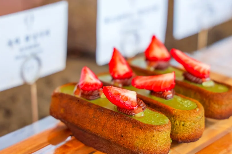 A close-up of three green cakes topped with fresh strawberries on a wooden display board. - 済州島・涯月（エウォル）の海を飲み込む贅沢。韓屋と絶景が織りなす『ヘジゲ（海知開）』完全ガイド